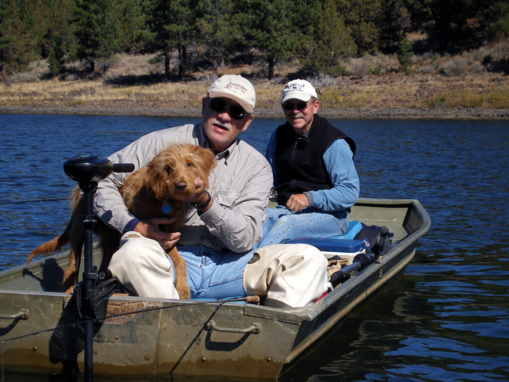 Two men and a dog in a small boat on Round Valley Reservoir in the fall